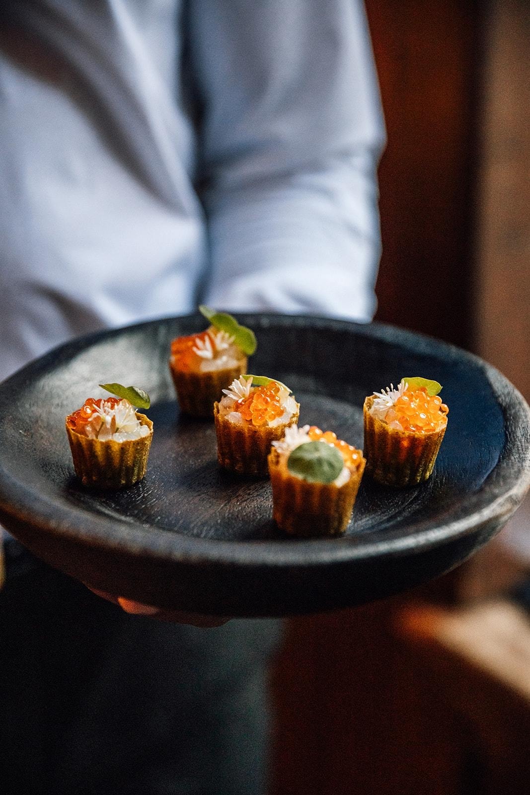 Canapés with salmon roe on dark plate
